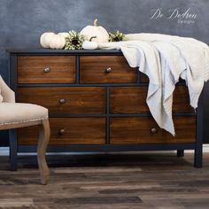 a dresser with a blanket on top of it and pumpkins sitting on the top