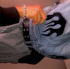 a person wearing a pair of jeans with flames on the side and a hand in their pocket