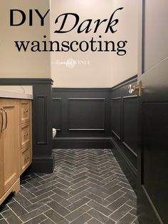 a bathroom with black and white walls, herringbone tile flooring and wooden cabinets