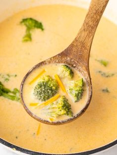 a wooden spoon filled with broccoli cheese soup