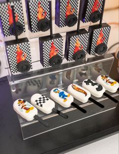 there are some cupcakes in the shape of cars on this display case with black and white checkers