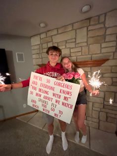 two young people holding sparklers and a sign