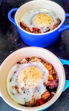 two blue bowls filled with food on top of a counter next to an egg in the middle