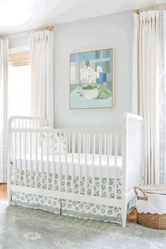 a baby's room with a white crib in the corner and paintings on the wall