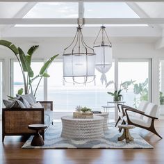 a living room with two chairs and a table in front of large windows that look out to the ocean