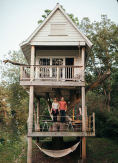 two people standing in front of a tree house