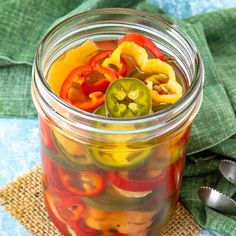 a jar filled with pickles and peppers on top of a burlied cloth