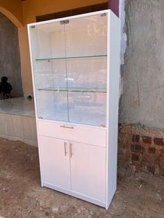 a white cabinet sitting on top of a dirt floor