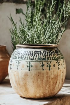 a vase sitting on top of a table next to a pot filled with green plants