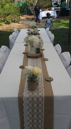 the table is set up with white flowers and burlock runneres on it