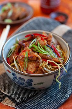 a bowl filled with meat and veggies next to chopsticks on a table