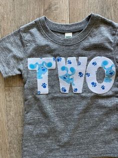 a t - shirt that says two with blue paw prints on the front and bottom