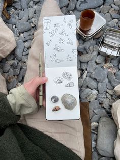 a person holding a pen and drawing rocks