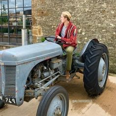 a man sitting on top of an old blue tractor