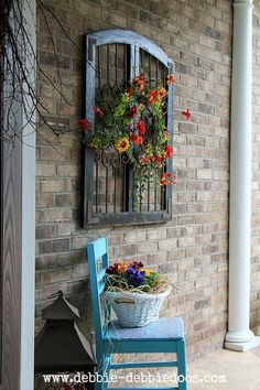 a blue bench sitting in front of a brick wall with a window and flowers on it