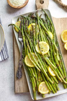 asparagus with lemons and herbs on a cutting board next to some bread