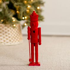 a red toy standing next to a christmas tree