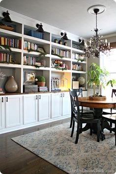 a dining room table and chairs with bookshelves in the background