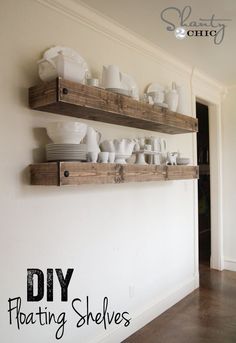 two wooden shelves filled with dishes on top of a white wall next to a doorway