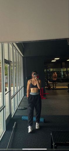 a woman taking a selfie in front of a gym window with her cell phone