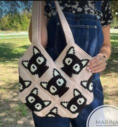 a woman is holding a crocheted bag in her hands and wearing overalls