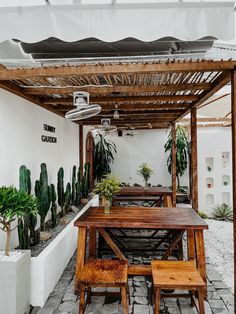 a wooden table sitting under a pergolated roof next to some potted plants