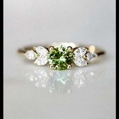 an engagement ring with a green and white diamond in the center, on a white surface