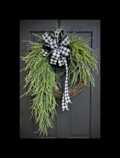 a black and white wreath hanging on the front door with a gingham bow