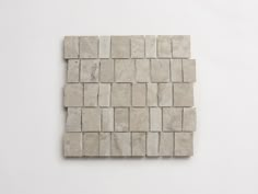 a white tile wall with square tiles on the bottom and one in the middle that has been cut into smaller squares