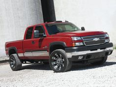 a red pick up truck parked in front of a white building with black rims