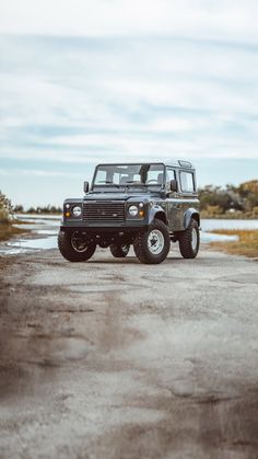 a black jeep parked on the side of a dirt road