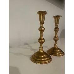 two brass candlesticks on a white surface