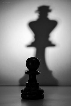 a black and white photo of a chess piece with the shadow of a man's head