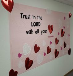 a bulletin board with hearts hanging from it's sides and the words trust in the lord with all your heart