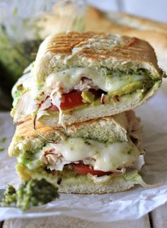 two sandwiches stacked on top of each other with broccoli and tomato in the background