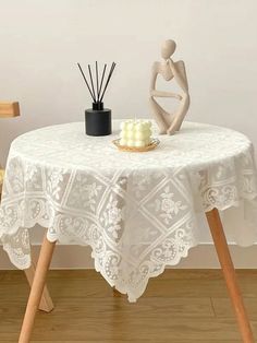 a white table with a candle and some candles on it next to a wooden chair