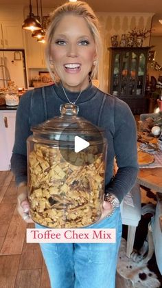 a woman holding a large glass jar filled with nuts and other things in her hands