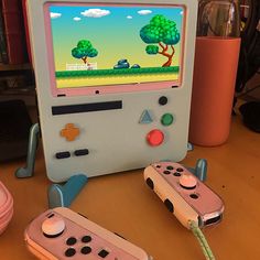 two nintendo wii game controllers sitting next to each other on a wooden table in front of a computer monitor