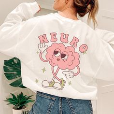 a woman wearing a white sweatshirt with the words neuro on it and a pink brain