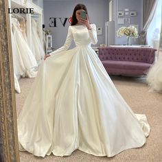 a woman taking a selfie in front of a mirror wearing a white wedding dress