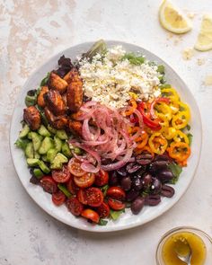 a white plate topped with lots of different types of food next to a glass of olive juice