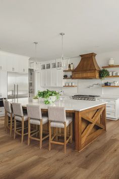 a kitchen with white cabinets and an island in the middle, surrounded by wooden flooring