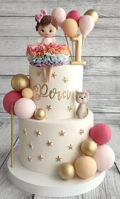 a birthday cake decorated with balloons and a girl on top