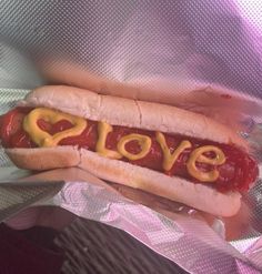 a hot dog with mustard and ketchup on it's bun that says love