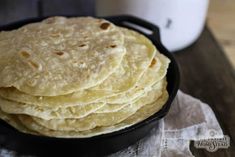 a stack of tortillas sitting in a pan on top of a wooden table