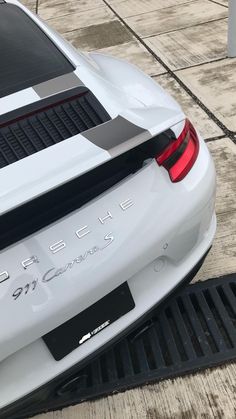 the back end of a white sports car parked in front of a parking space mat