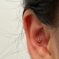 a woman's ear with a small gold flower on it