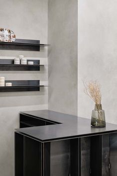 a vase with some flowers in it sitting on a table next to shelves and candles