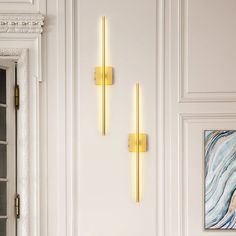 two wall sconces are mounted to the side of a white door with gold trim