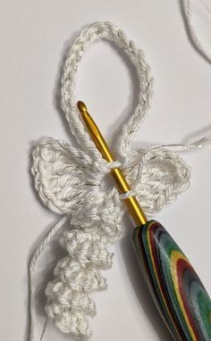 a crocheted umbrella with a gold handle on a white tablecloth next to a hook